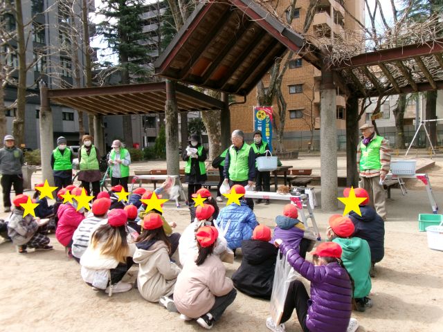 樹名板の付け替えの説明を聞いている小学生たちの画像