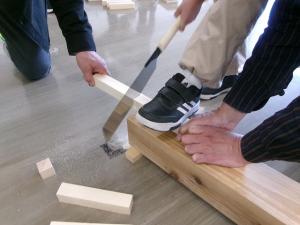 のこぎりで木を切っている様子